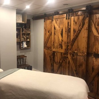 Treatment room with signature rustic barn doors, white linens on massage table, warm wood tones at Hands On Health