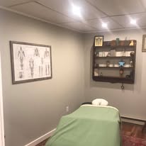 Treatment room with framed anatomy artwork on walls, massage table, professional clinical atmosphere