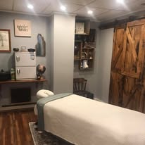 Treatment room with rustic barn sliding doors, massage table with white sheets