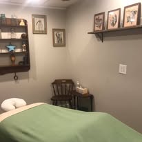 Treatment room corner with framed artwork, green sheets, warm ambient feel